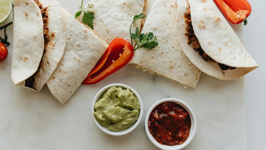 Tacos with guacamole and salsa on marble.