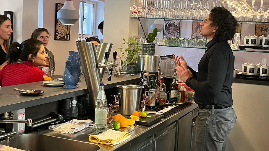 Barkeeper erklärt Cocktail-Zubereitung aufmerksamem Publikum.