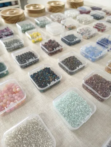 Verschiedene bunte Perlen in kleinen Plastikboxen.