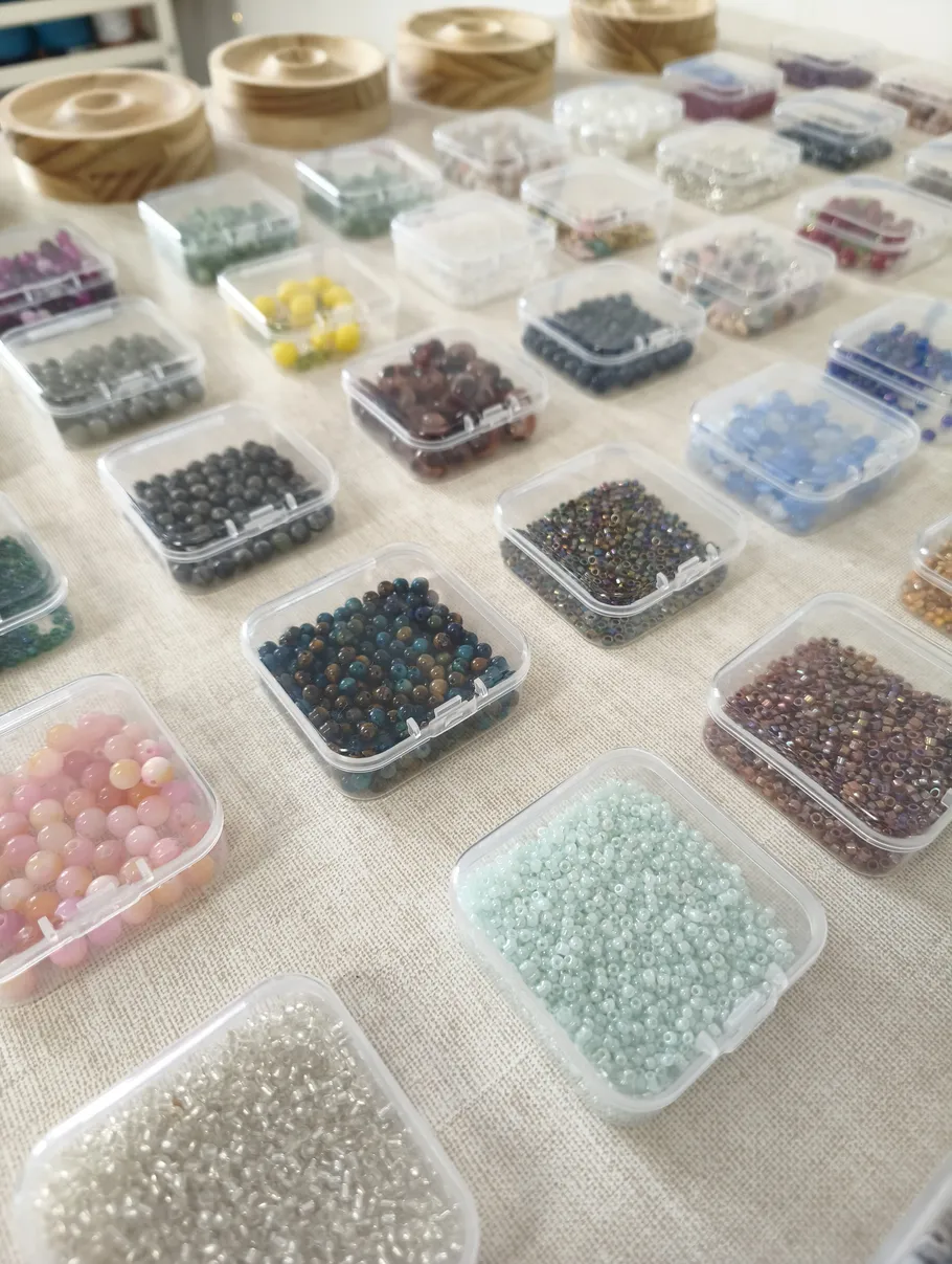 Various colorful beads in small transparent boxes.