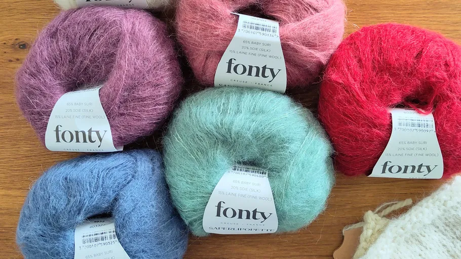 Six colorful yarn balls on wooden surface.