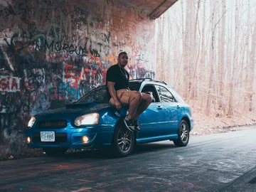 Blauer Wagen, Mann sitzt drauf, umgeben von Graffiti.