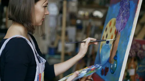 Woman painting colorful canvas in studio.