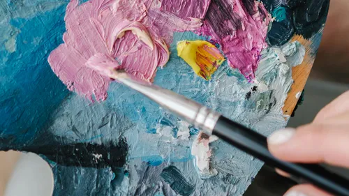 Pinsel mischt bunte Farbe auf Palette.