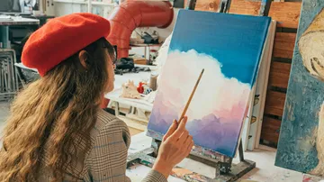 Frau malt Landschaft im Atelier.