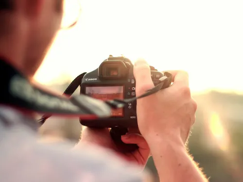 A camera is held to photograph a sunset.