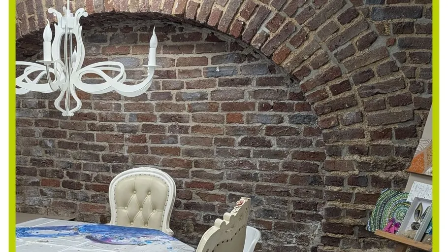 Dining table and chandelier in brick room.