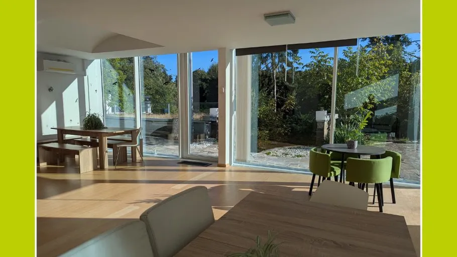 Modern room with large windows and greenery.