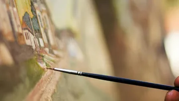 Pinsel trägt Farben auf eine Landschaftsleinwand auf.
