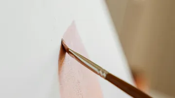 Pinsel trägt braune Farbe auf Leinwand auf.