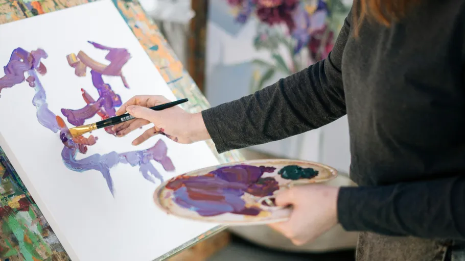 Artist painting abstract purple artwork indoors.