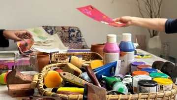 Art supplies and people creating crafts at table.