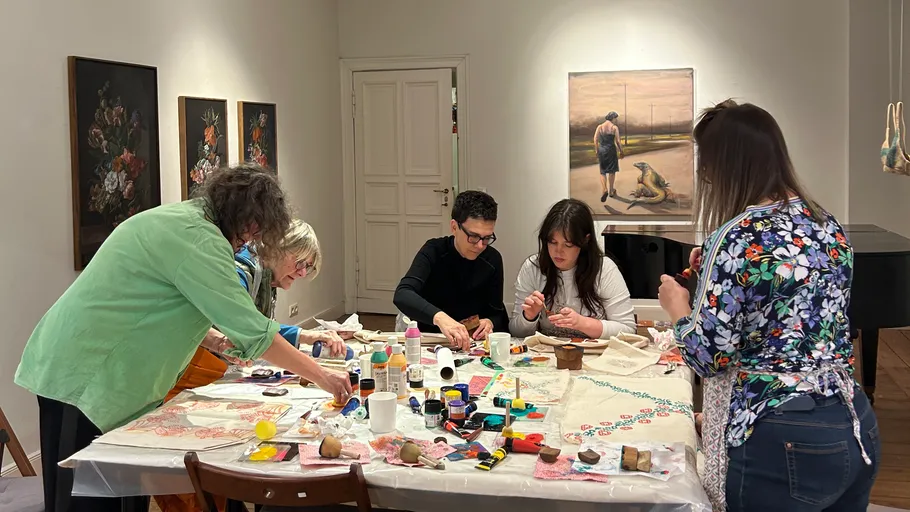 People crafting with paints at a table indoors.