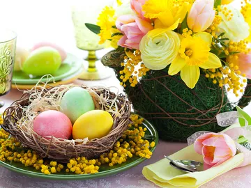 Colourful eggs lie in a nest with flowers.