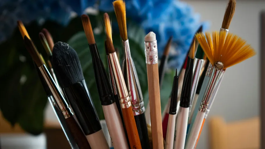 Various paintbrushes in a holder, blurred background.