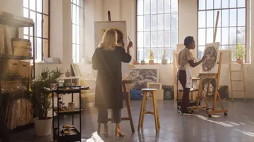 Zwei Künstler malen in einem sonnigen Atelier.