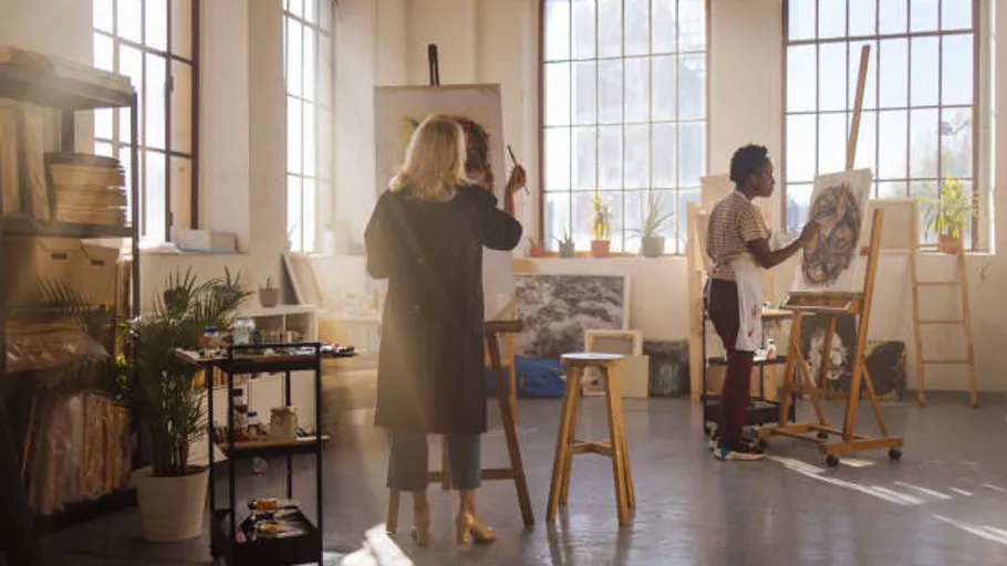 Two artists painting in a sunlit studio.