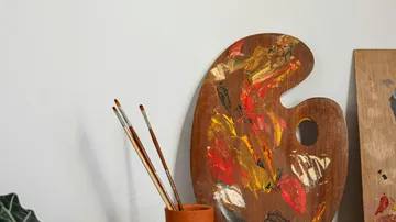 Farbpalette mit Pinseln auf Tisch.