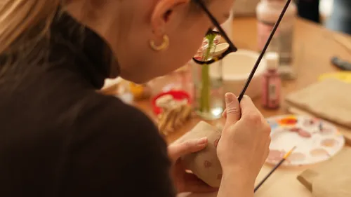 Woman painting pottery in art studio.