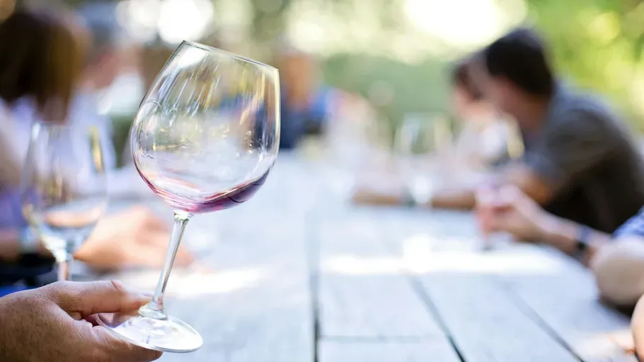 Wine glass held outdoors during gathering.