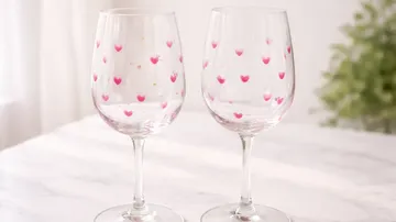 Two wine glasses with pink hearts, indoors.