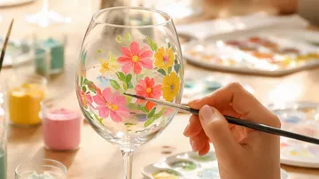 Hand painting flowers on a wine glass.