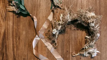 Floral wreath with ribbons on wooden table.