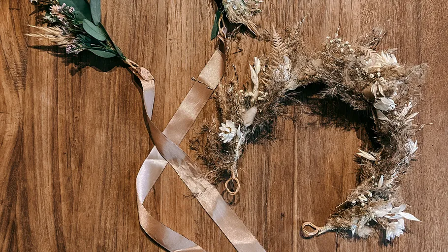 Floral wreath with ribbons on wooden table.