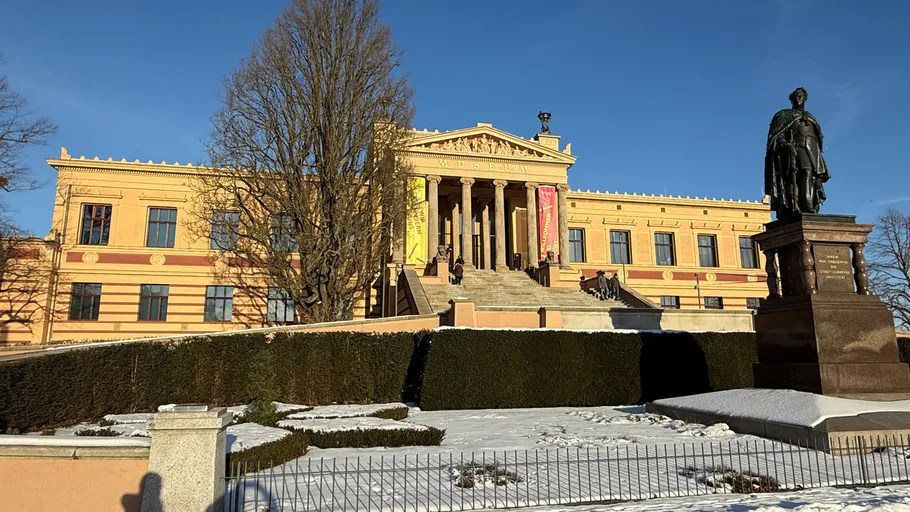 Historic building and statue in snowy landscape.