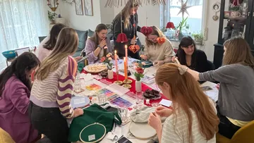 Gruppe bastelt an festlich gedecktem Tisch.