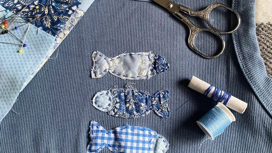 Fabric fish sewn onto blue textile background.