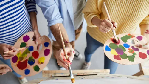 People painting with palettes and brushes.