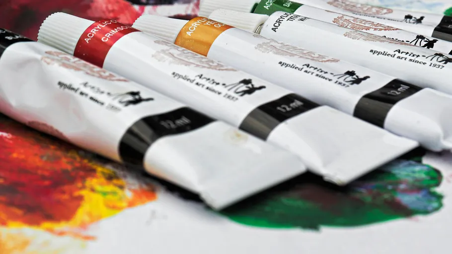 Acrylfarbtuben auf verschmierter bunter Palette.