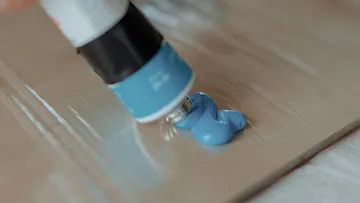 Blaue Farbe aus Tube auf Unterlage gedrückt.