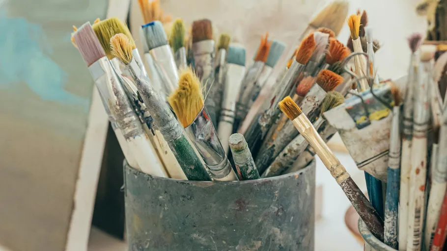 Paintbrushes in a container on an artist's table.