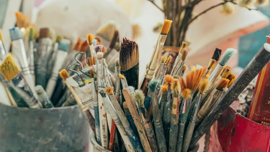 Paintbrushes in jars on an artist's table.