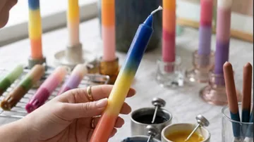 Hand hält bunte Verlaufs-Kerze drinnen.
