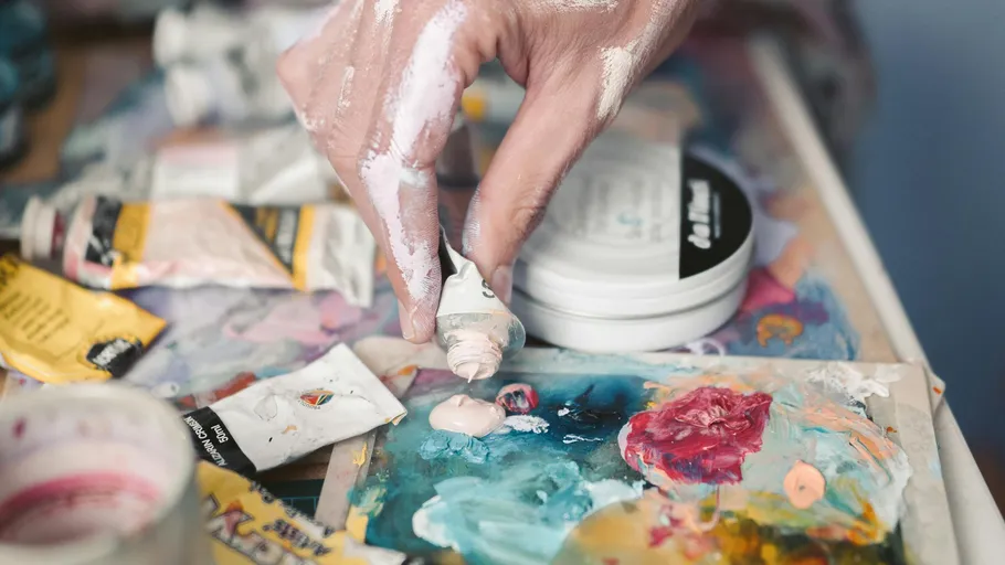 Hand drückt Farbe auf bunte Palette.