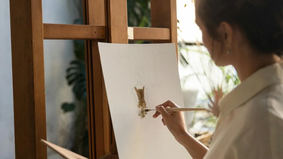 Person painting on canvas in natural light.