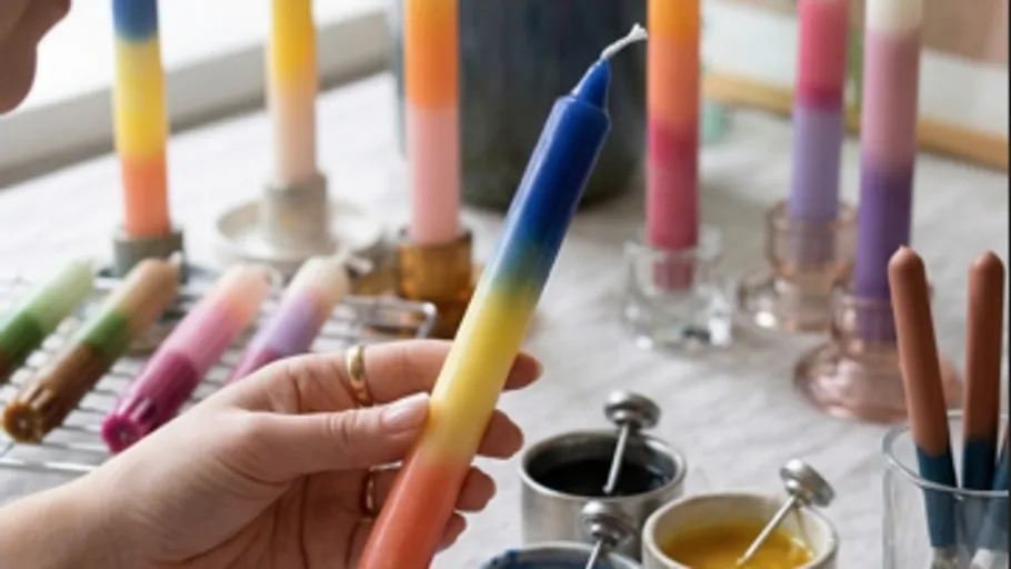Hand hält bunte Verlaufs-Kerze drinnen.