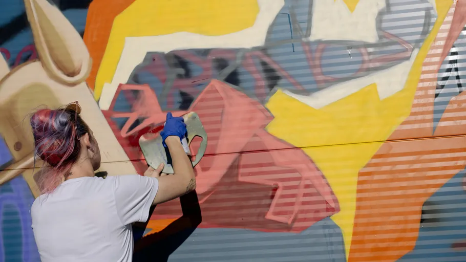 Person spray painting colorful wall mural.