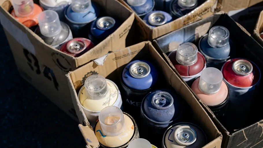 Spray paint cans in cardboard boxes outdoors.