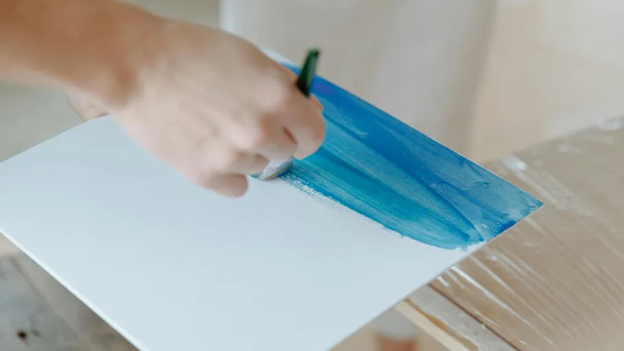 Hand painting blue brushstroke on canvas.