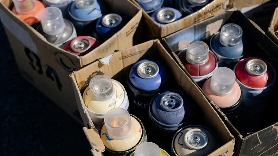 Spray paint cans in cardboard boxes outdoors.