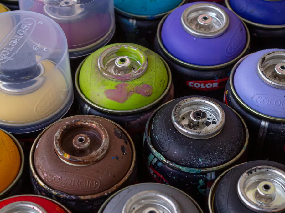 Colorful spray paint cans arranged closely together.
