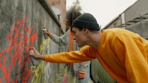 Two people spray painting a concrete wall.
