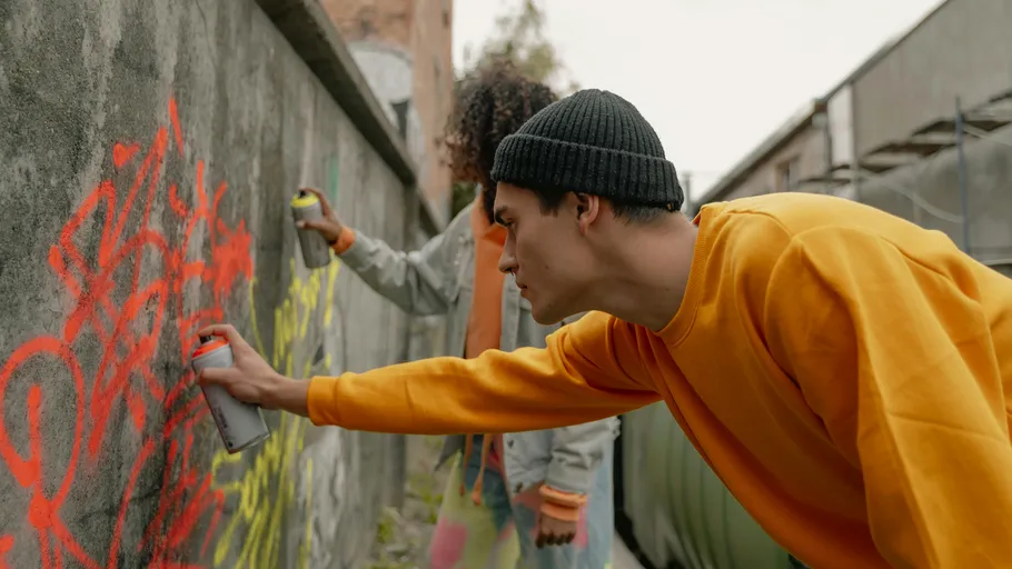Two people spray painting a concrete wall.