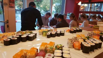 Verschiedene Sushi-Platten in einem belebten Restaurant.