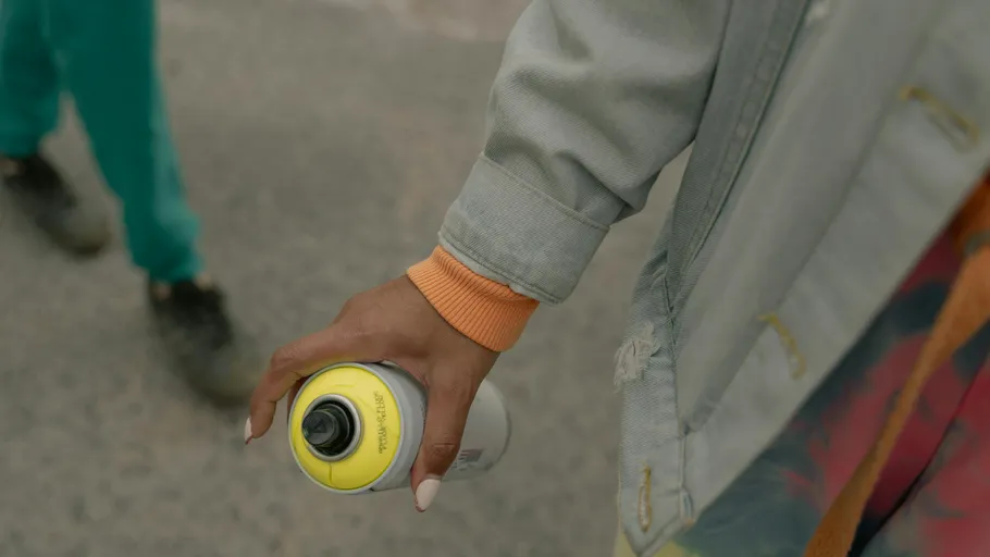 Person holding a spray can on street.
