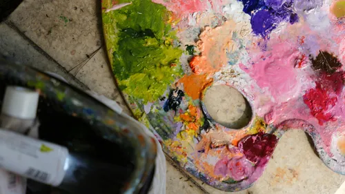 Colorful artist palette with mixed paints on floor.